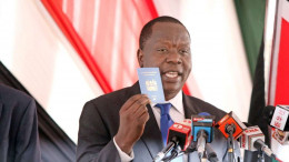 Interior CS Fred Matiang'i displays the new e-passport launched in 2017.