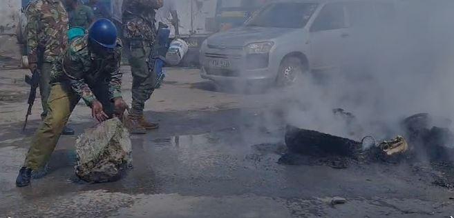 Police officer clearing a road barricaded in Mombasa.